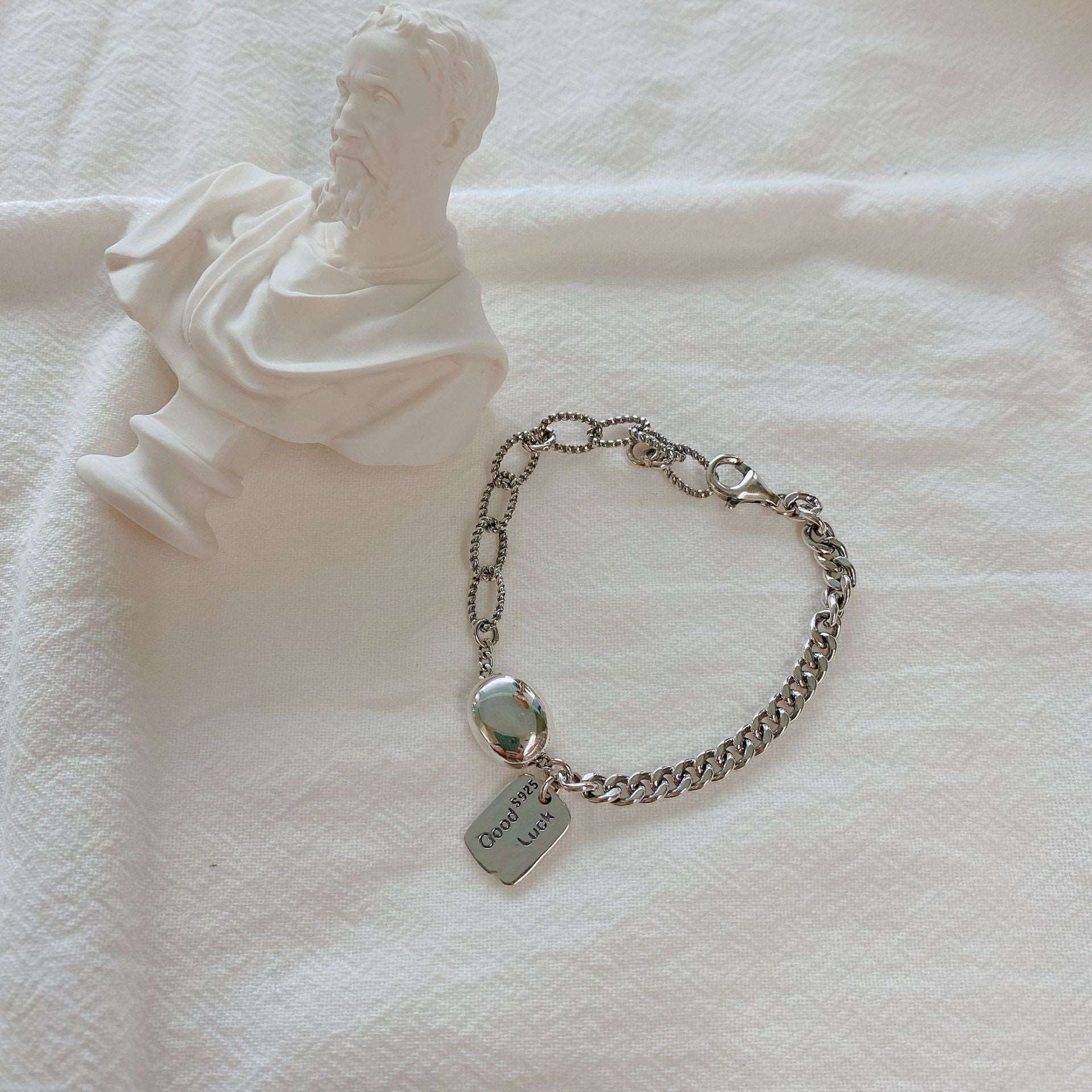 925 Silver Good Luck Bracelet beside man's statue